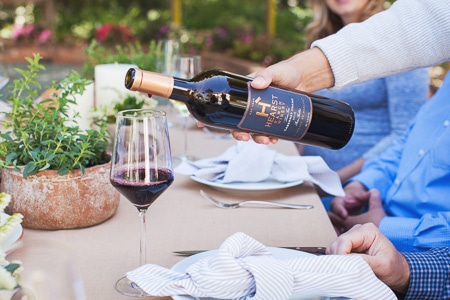 A bottle of 2016 Cabernet Franc from Hearst Ranch Winery being poured into a wine glass.