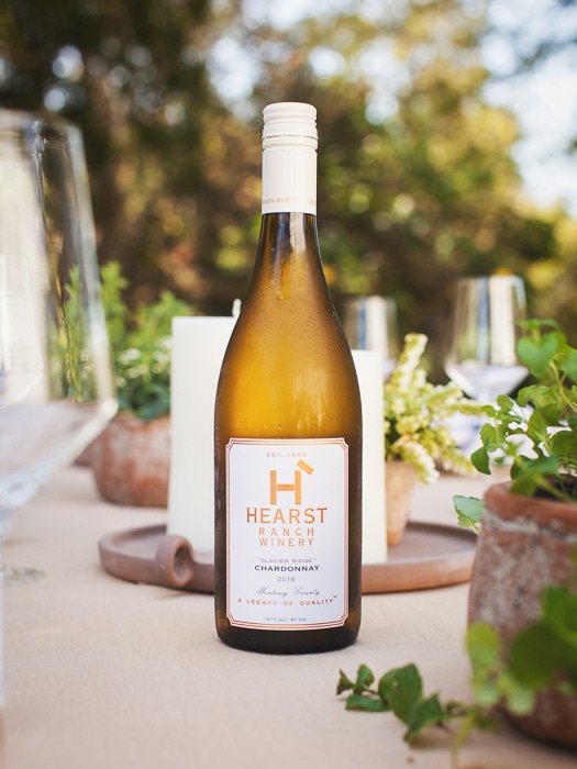 A bottle of 2016 Chardonnay from Hearst Ranch Winery sitting upright on a table.