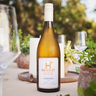 A bottle of 2016 Chardonnay from Hearst Ranch Winery sitting upright on a table.